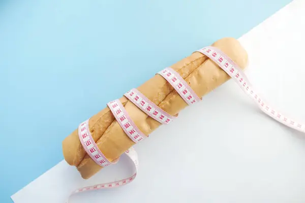 Slice of whole meal bread and measurement tape on table . — Stock Photo, Image