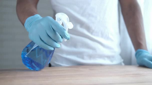 Hand in blauwe rubberen handschoenen met spuitfles reinigingstafel — Stockvideo