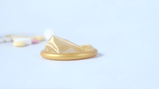 Zblízka kondom a lékařské pilulky na bílém — Stock video