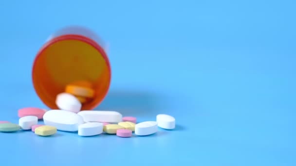 Veel kleurrijke pillen en capsules morsen op blauwe achtergrond — Stockvideo