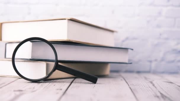 Stack of book and magnifying glass on table. — Stock Video