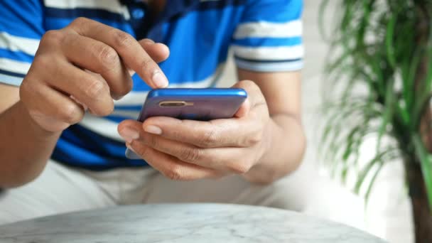 Tangan pemuda menggunakan telepon pintar sambil duduk — Stok Video