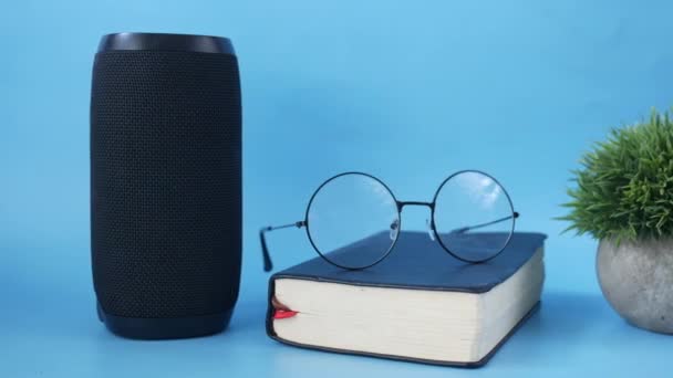 Smart speaker en boek over blauwe achtergrond — Stockvideo