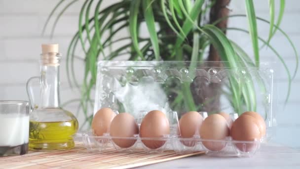 Huevos en una caja de plástico, leche, aceite y nuez en la mesa — Vídeos de Stock