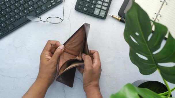 Junger Mann öffnet leere Geldbörse auf Tisch — Stockvideo