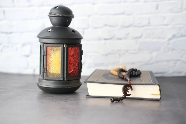 Luce della lanterna, Libro santo Corano e rosario sulla tavola, da vicino. — Foto Stock