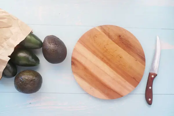 Vista superior de fatia de abacate e tábua de corte na mesa — Fotografia de Stock