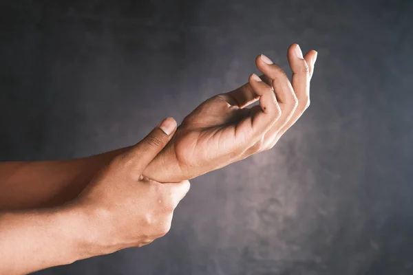 Mann mit Schmerzen in der Hand vor schwarzem Hintergrund — Stockfoto