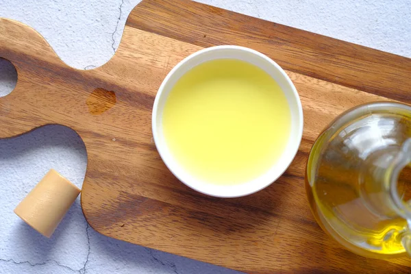 Minyak zaitun dalam wadah pada papan potong — Stok Foto
