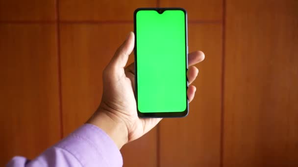 Primer plano de la mano del hombre joven utilizando el teléfono inteligente con pantalla verde — Vídeos de Stock