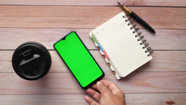 Bovenaanzicht van de mens zetten smart phone en koffiekop op tafel — Stockvideo