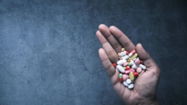 Vue de dessus de nombreuses pilules et capsules colorées sur la paume de la main sur le noir — Video
