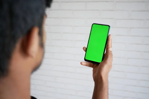 Rückansicht der Hand eines jungen Mannes mit Smartphone mit grünem Bildschirm — Stockfoto