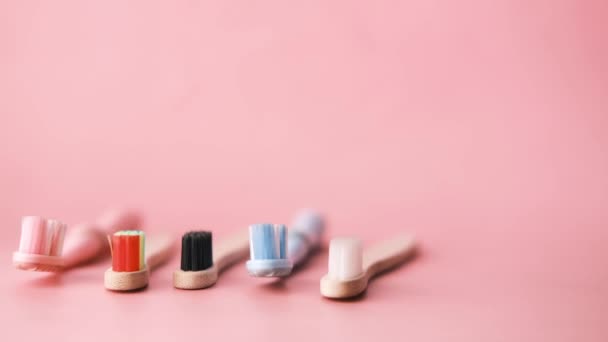 Cepillos de dientes de colores sobre un fondo rosa — Vídeos de Stock