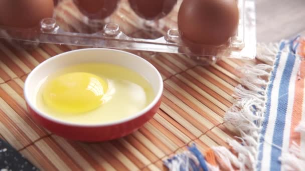 Memecahkan telur dan menuangkan ke dalam wadah kecil di atas meja , — Stok Video