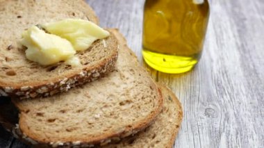 Bir dilim tereyağlı ekmek ve masada bir şişe yağ. 