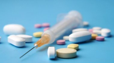 Mavi arka planda şırınga ve haplar, kapatın.