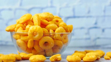 Beyaz arka planda siyah kasede şişirilmiş mısır halkaları çipleri