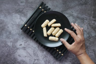 Tabaktaki lezzetli yulaf çubuklarını elle seç. 