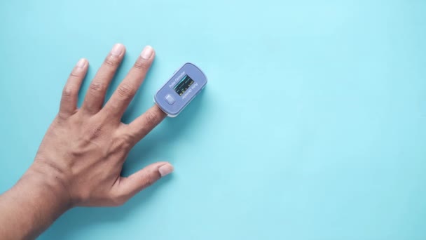 Närbild av manlig hand med pulsoximeter på blå bakgrund — Stockvideo
