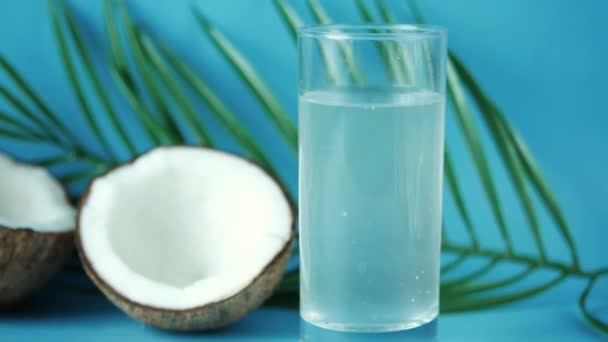 Plak verse kokosnoot en glas kokoswater op tafel — Stockvideo
