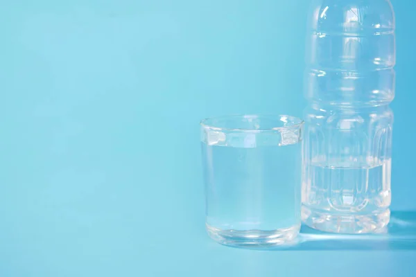 Água potável fresca em uma garrafa de plástico e vidro de água em azul — Fotografia de Stock