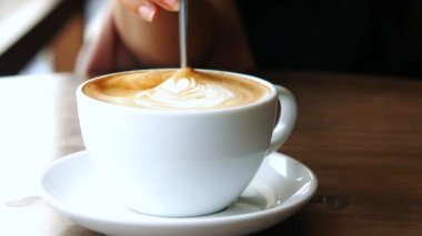 İnsan, kaşıkla kahve karıştırır..