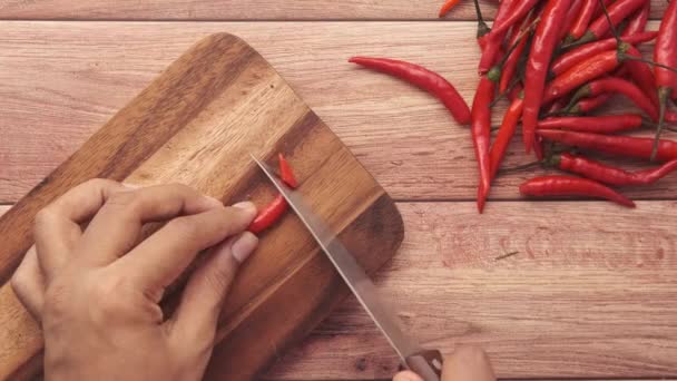 Osoba ruční řezání červené chilli na sekací desce — Stock video