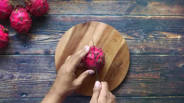 Jeune homme coupant un fruit dragon sur une planche à découper. — Video