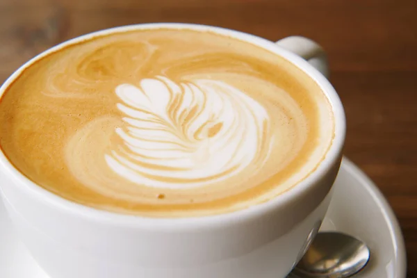 Uma xícara de café tarde com design de forma de flor no topo no café — Fotografia de Stock