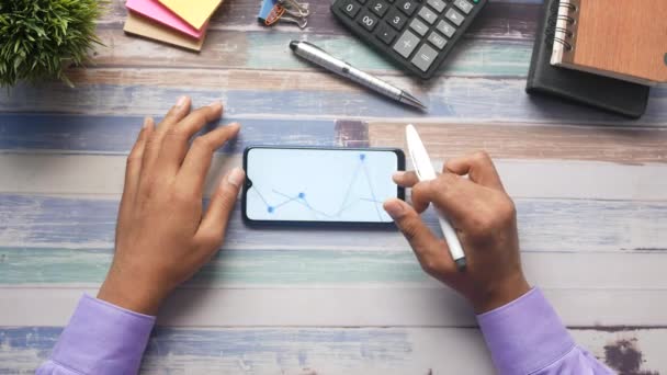 Jovem homem analisando gráfico de ações no telefone inteligente — Vídeo de Stock