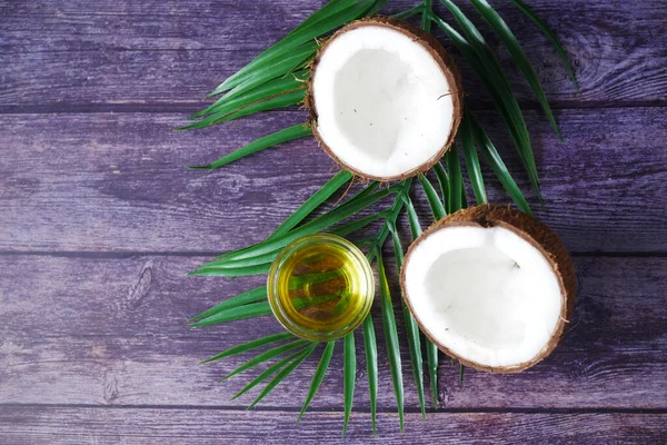 Ломтик свежего кокоса и бутылка масла на столе — стоковое фото