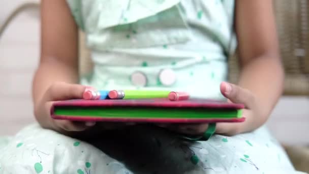 Close-up van de hand van het kind houden van een notitieblok zitten op een stoel — Stockvideo