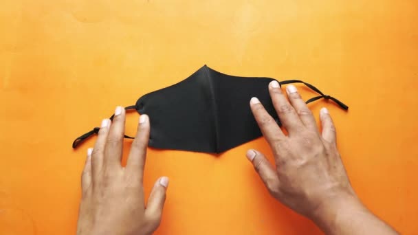 オレンジ色の表面に外科用フェイスマスクを持つ男性の手の上からの眺め — ストック動画