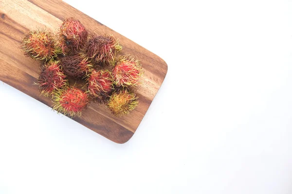 Pile de rambutan dans une planche à découper sur fond blanc — Photo