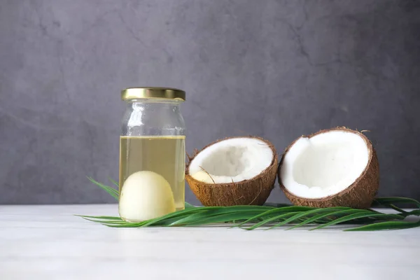 Parte de coco fresco e garrafa de óleo em uma mesa — Fotografia de Stock