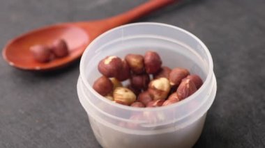 Siyah arkaplanda bir kabın içinde fındıklar,