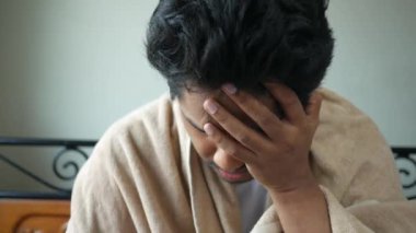 Yatakta otururken battaniye içinde öksüren olgun bir adam. 