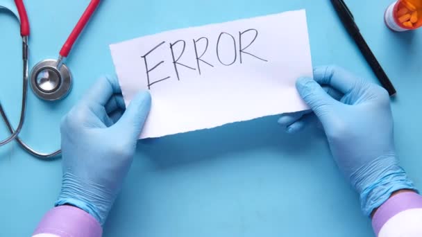 Holding medical error text on a paper with pills and stethoscope on table . — Stock Video