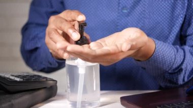 İş adamı ofis masasında dezenfektan jeli kullanıyor. 