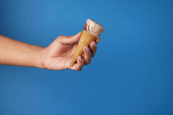 Mão pessoa segurando sorvete contra fundo azul com espaço de cópia — Fotografia de Stock