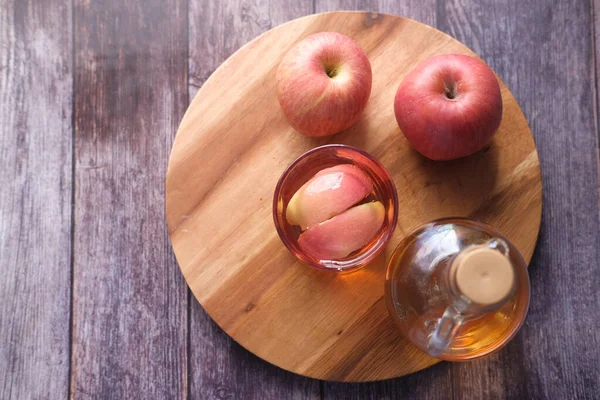 Äppelvinäger i glasflaska med färskt grönt äpple på bordet — Stockfoto