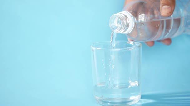 Versando acqua in un bicchiere su uno sfondo blu con spazio di copia — Video Stock