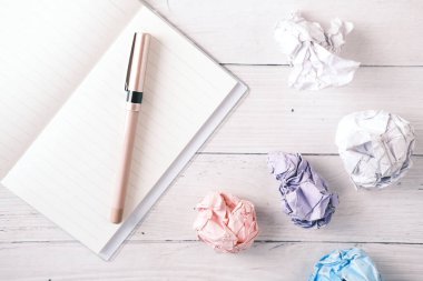 Buruşmuş kağıt top ve not defteri ahşap masanın üzerinde..