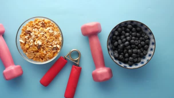 Haltère, petit déjeuner aux céréales et baies bleues dans un bol sur la table — Video