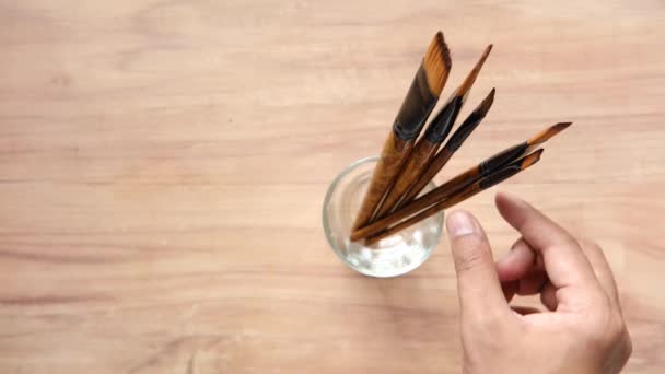 Hand pick kunst borstel in een glas op tafel met kopieerruimte — Stockvideo