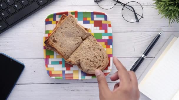 Sandwich aux légumes cueillette à la main sur une pâtée sur une table de bureau . — Video