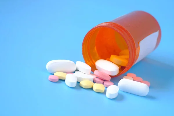 Primo piano di molte pillole colorate e capsule su sfondo blu — Foto Stock