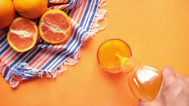 다양 한 색깔의 배경 위에 오렌지 주스를 붓는 모습 — 비디오