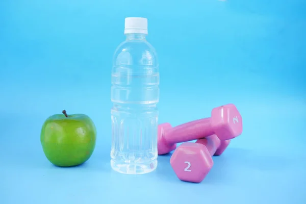 Fresh drinking water, apple and a pink color dumbbell on table — Stock Photo, Image